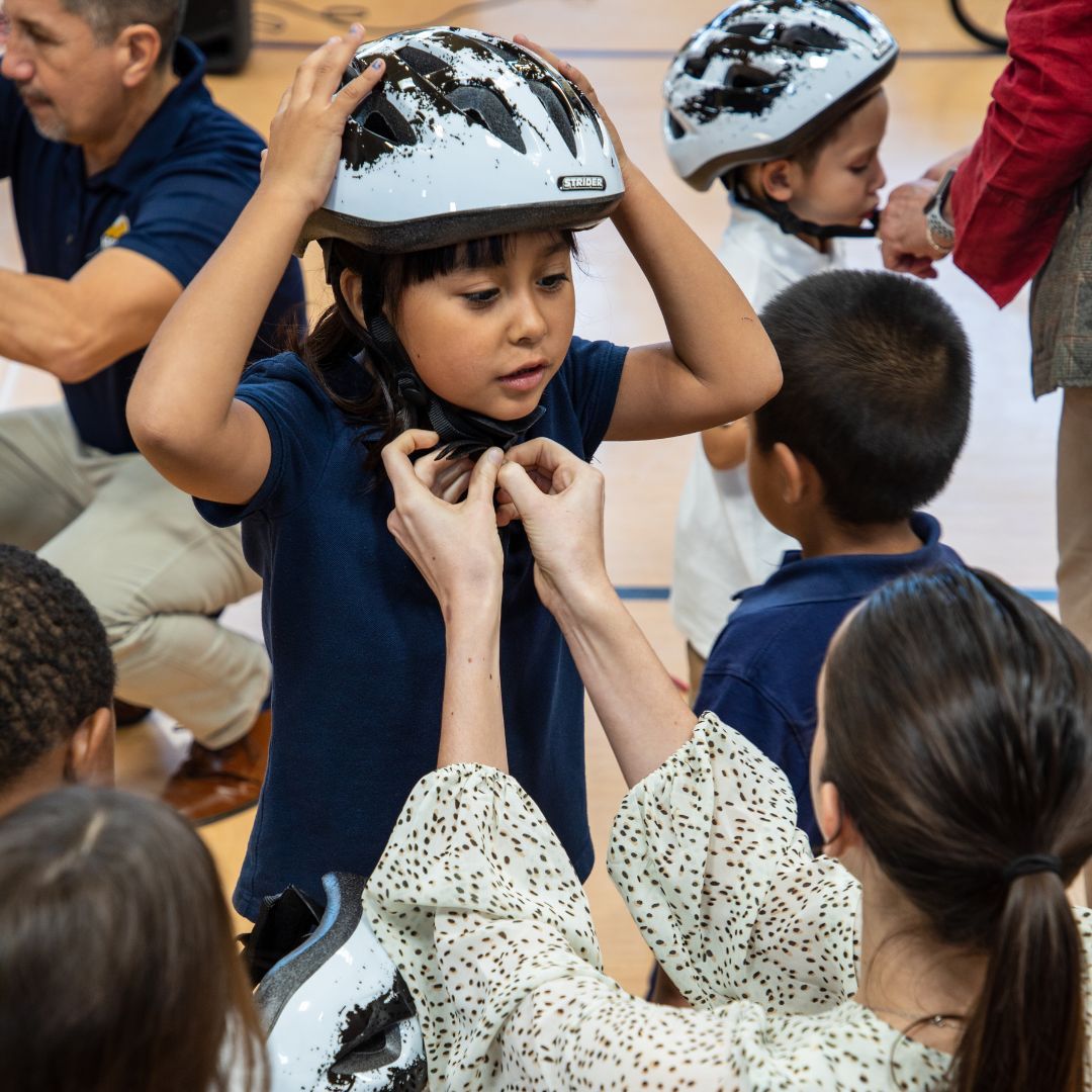 Student fitting bike helmet on head
