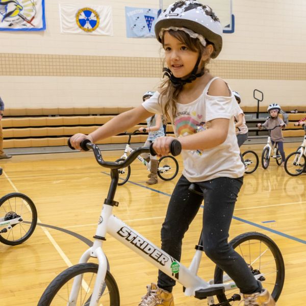 Student riding bike in kindergarten PE class