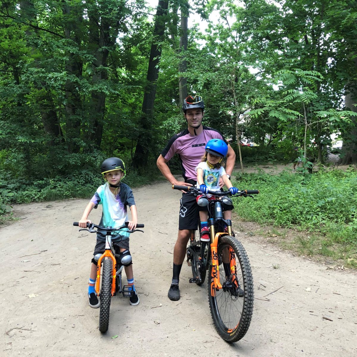 All Kids Bike ambassador Francisco "Chico" Lachowski and his two sons riding orange mountain bikes