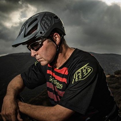 Dave Cullinan poses outdoors in cycling gear against a stormy sky.