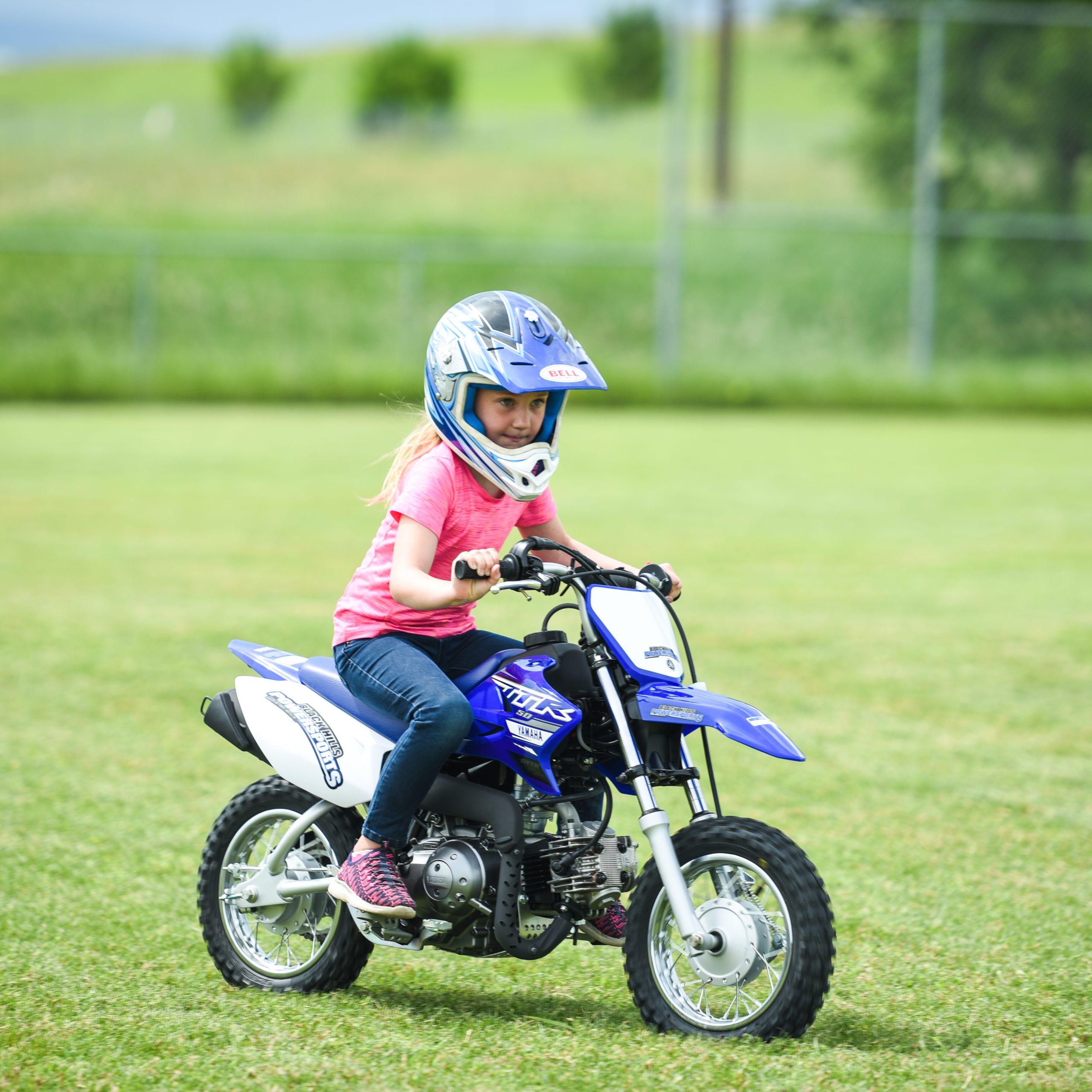 Young girl riding little dirt bike on the grass