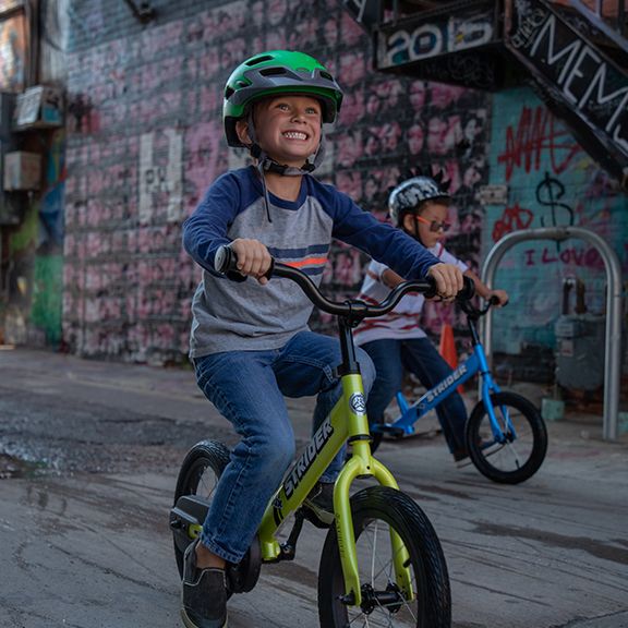 Young boy smiling while pedaling green 14x Sport