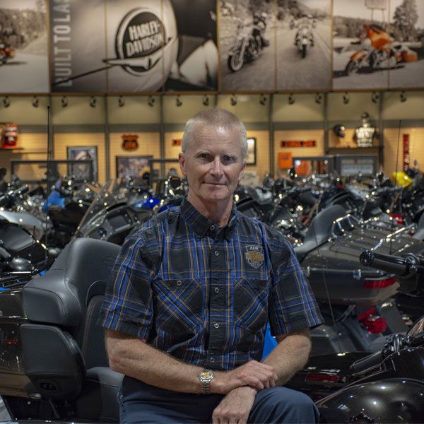 All Kids Bike president Al Rieman poses inside a Harley Davidson showroom with motorcycles in the background