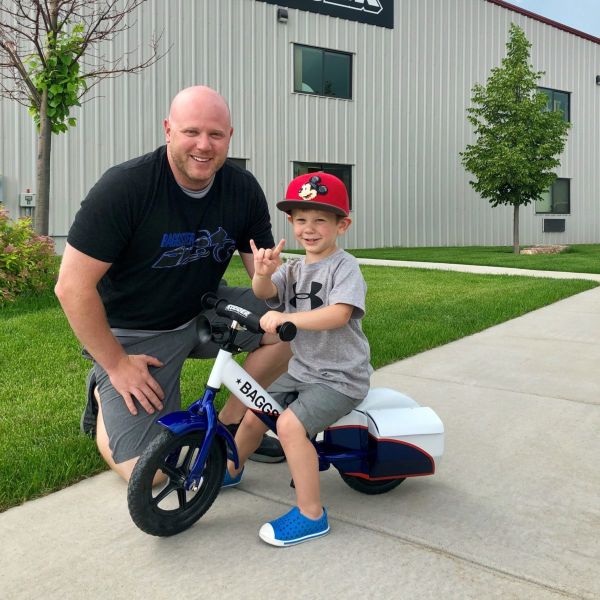 Blackout Industries owner and All Kids Bike ambassador James Washnok and his son pose on a custom built bike outside Strider headquarters in Rapid City, South Dakota