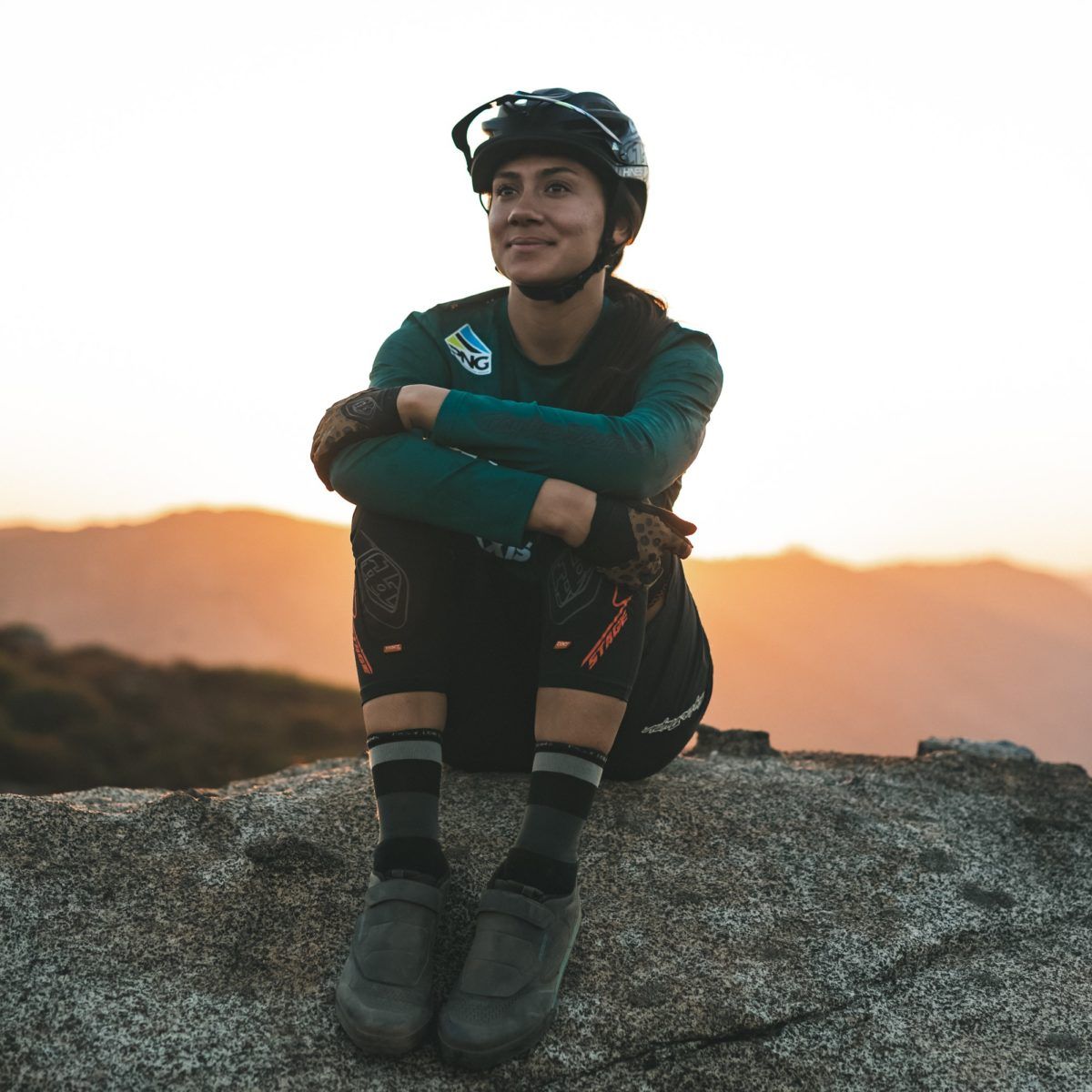 All Kids Bike ambassador Kialani Hines sits on a rock with the sun behind her.