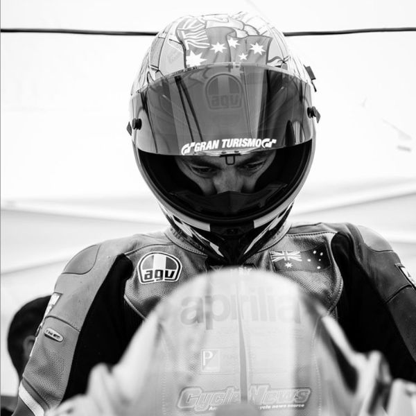 A black and white portrait of All Kids Bike ambassador Rennie Scaybrook on a motorcycle with his face obscured by a riding helmet