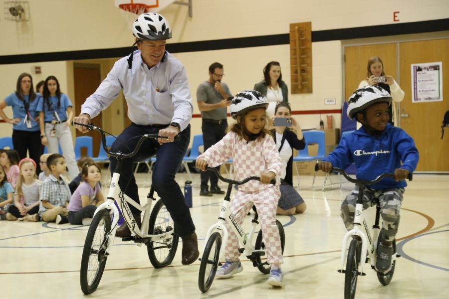 Nebraska Governor, Jim Pillen, riding a bike alongside kindergarten students
