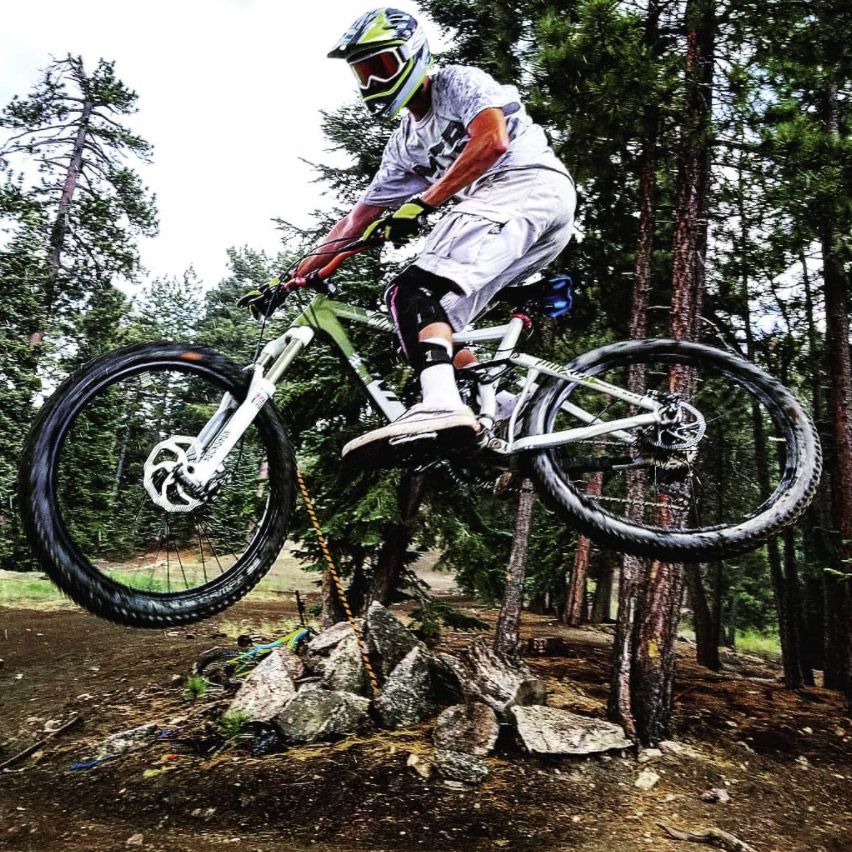 All Kids Bike ambassador Shawn Thacker jumps his mountain bike on a forest trail