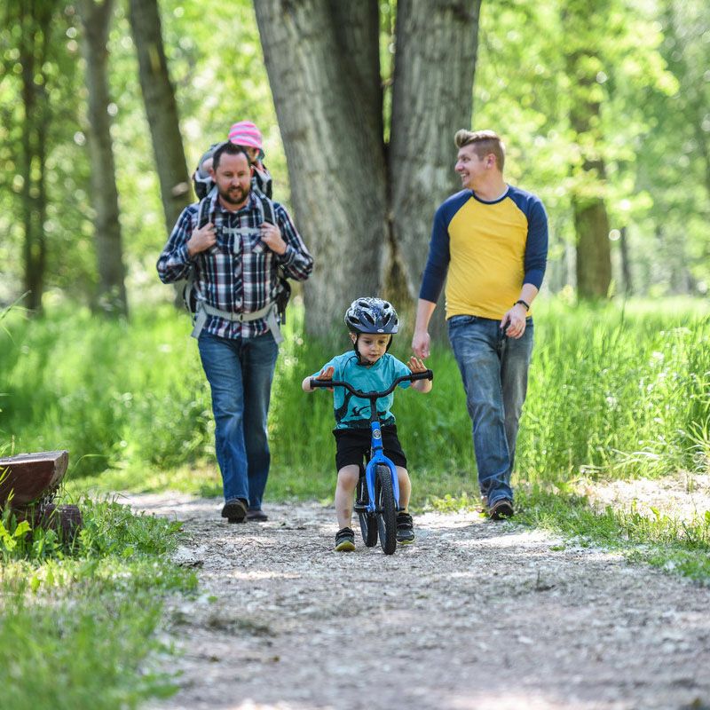 Family walking while kid rides bike