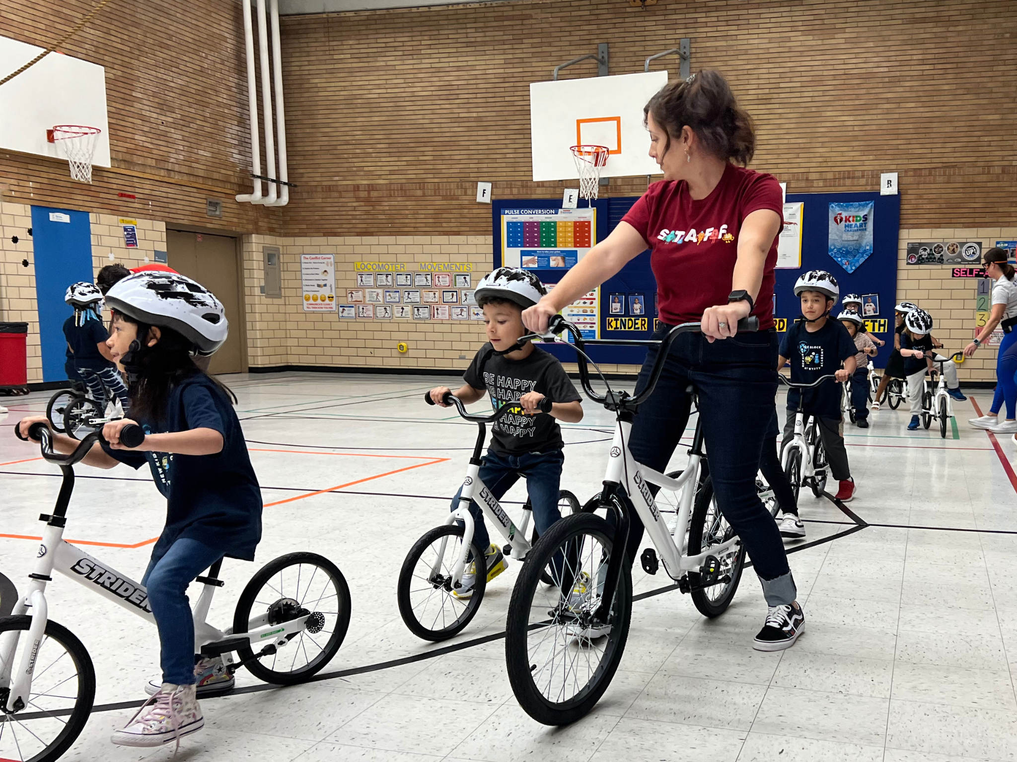 PE teacher instructing how to ride a bike in kindergarten PE class