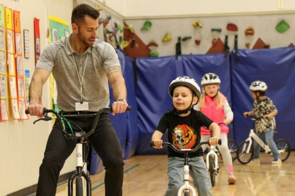 PE teacher instructing child how to ride bike in gym class