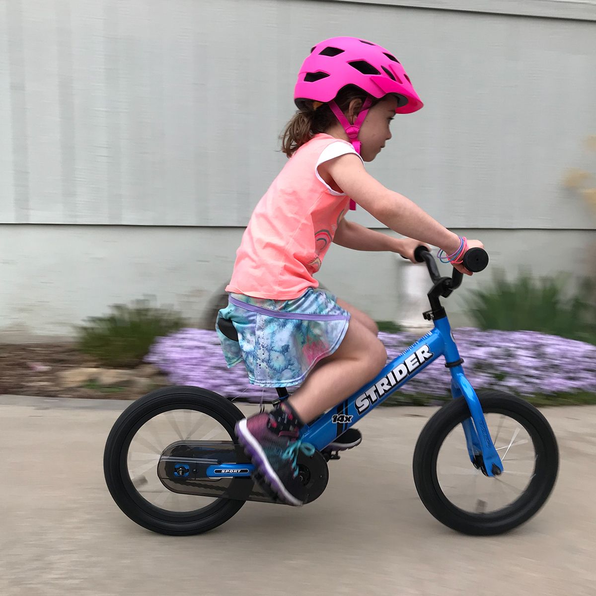 Girl focusing on her path while pedaling a blue 14x Sport