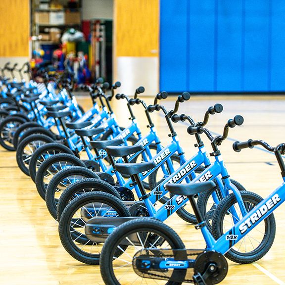 Row of blue 14x bikes lined up in gymnasium