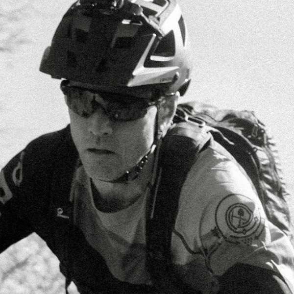 a black and white picture of Dave Wiens riding on a trail
