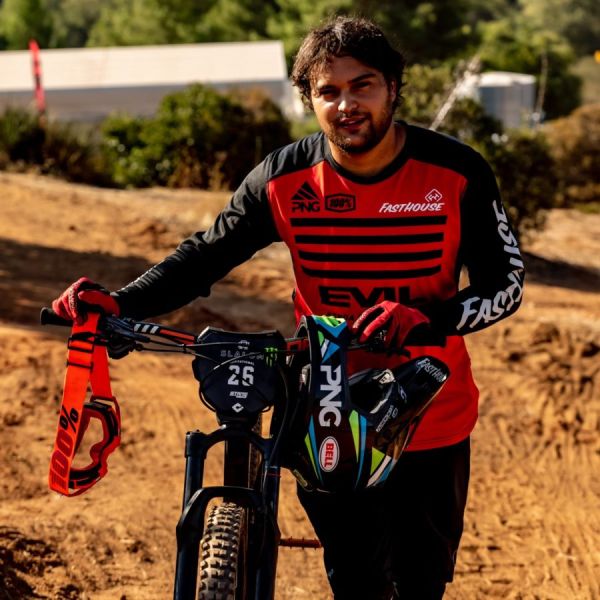 Austin Warren walking his mountain bike on a dirt track